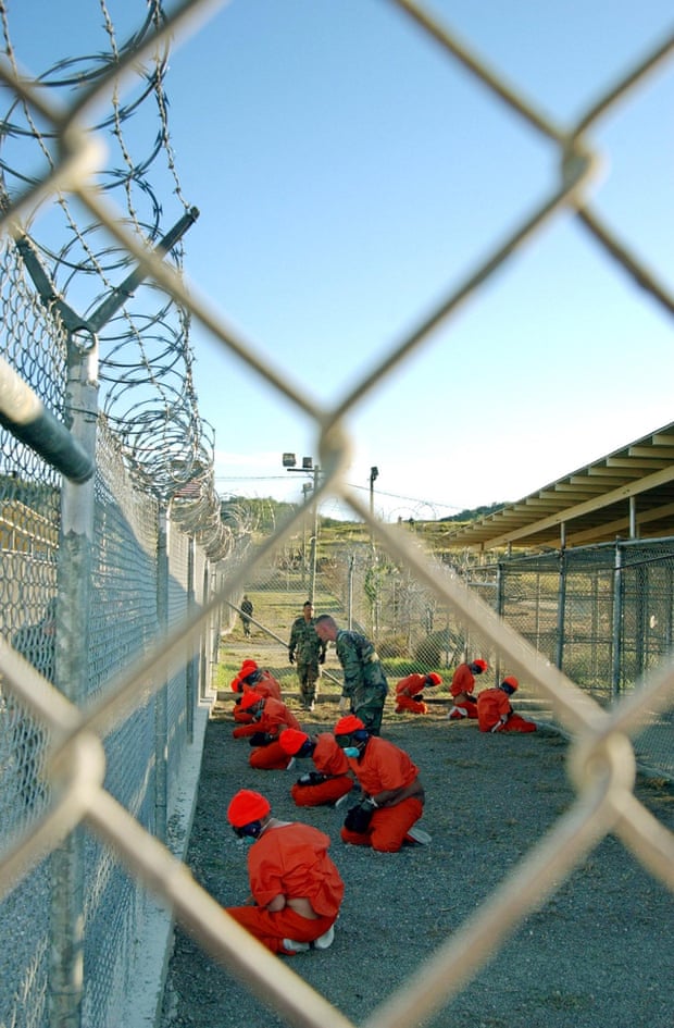 Los detenidos se sientan en un rea de detencin bajo la vigilancia de la polica militar estadounidense en Guantnamo en enero de 2002.