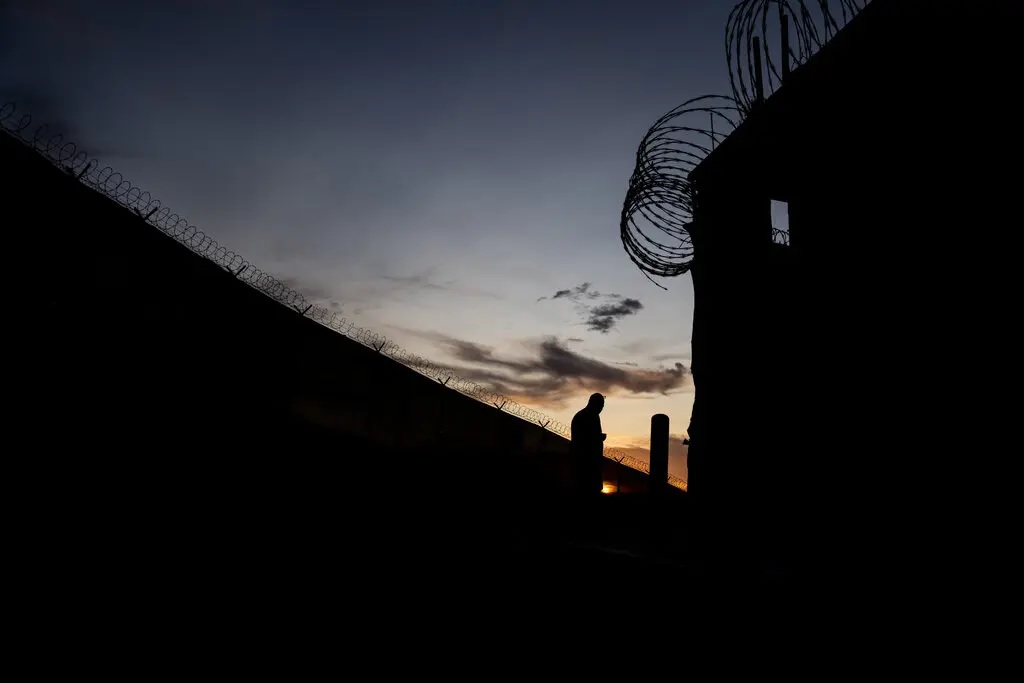 A silhouette of an individual against the sky with razor wire fencing at Guantánamo Bay Naval Base, Cuba.