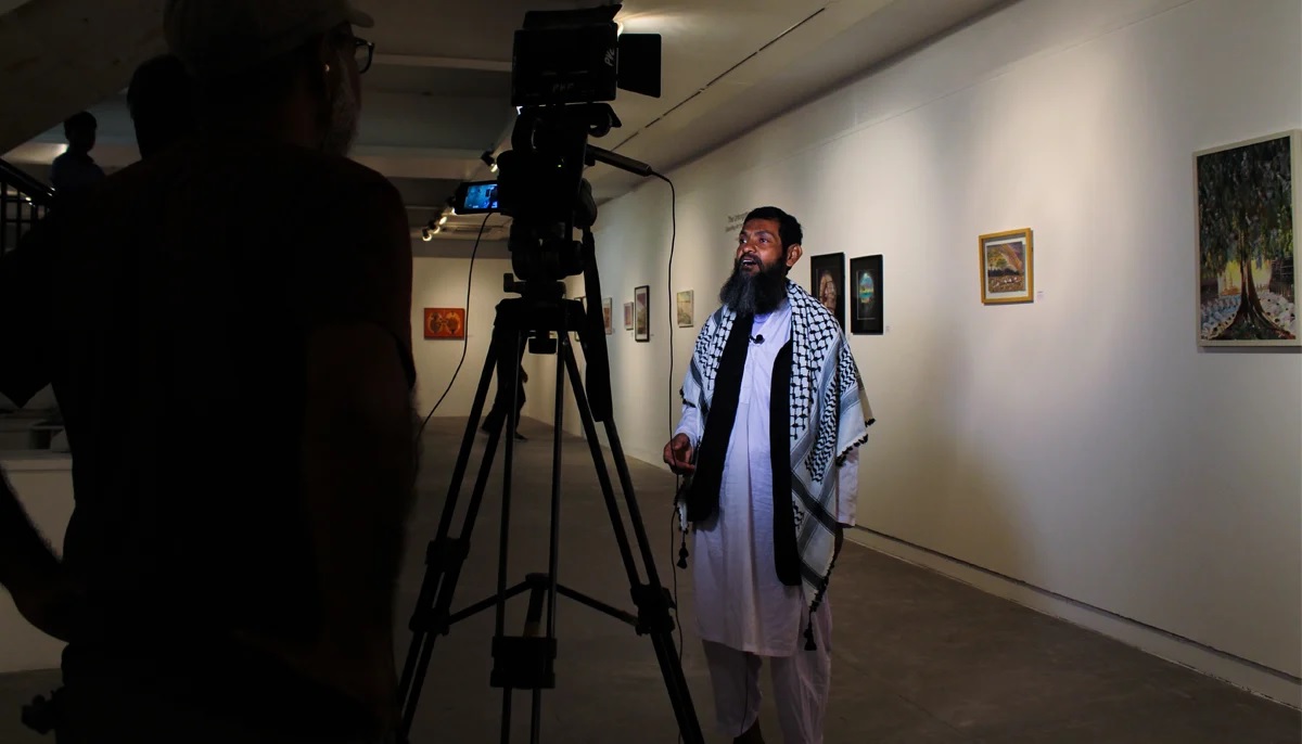 Ahmed gives an interview to a news outlet during his exhibition at IVS art gallery.  Photo by Hassaan Ahmed