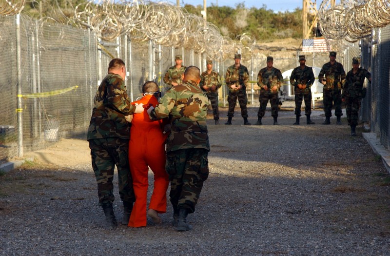 <p>Dos integrantes de la polica militar del Ejercito de Estados Unidos trasladan a un detenido en Guantnamo el 11 de enero de 2002.</p>