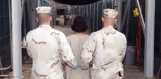 Dos soldados trasladan a un detenido en un campo de prisioneros de Guantnamo. Foto: Wikimedia